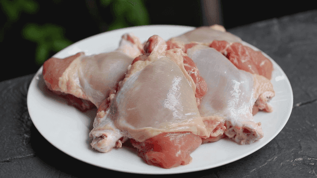 Raw chicken pieces on a white plate