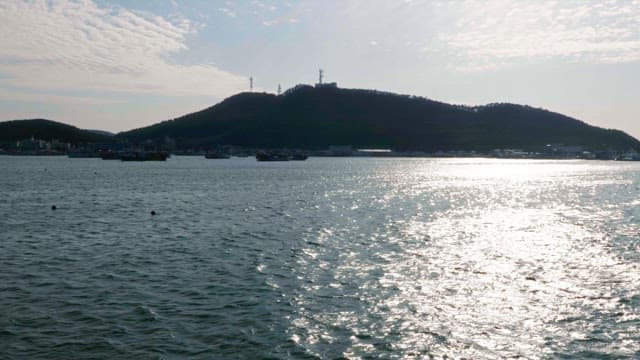 Silhouette of a mountain with boats on the calm sea