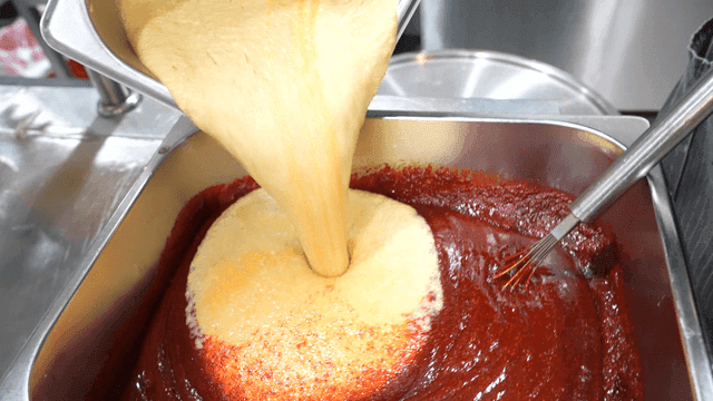 Ground fruit poured into gochujang in kitchen