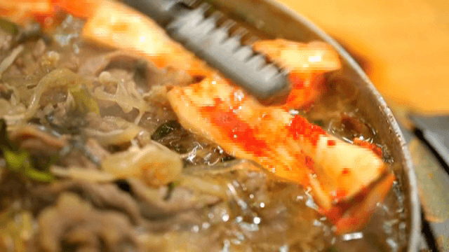 끓고있는 불고기 전골에 김치를 넣는 모습