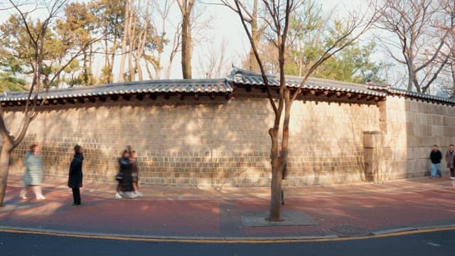 People walking along a traditional Korean wall