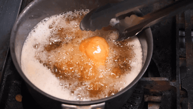 Potatoes being fried in hot oil in pan