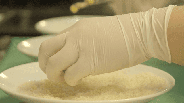 Chef breading with gloved hands