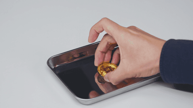 트레이에서 비트코인을 집어드는 손