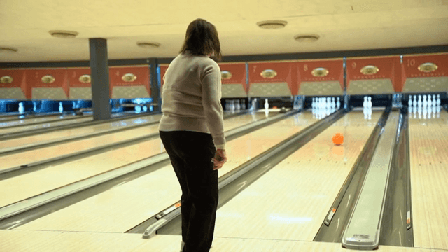 실내 볼링장에서 볼링을 치는 사람