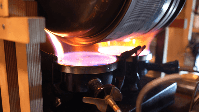 Flame heating metal roasting drum on stove