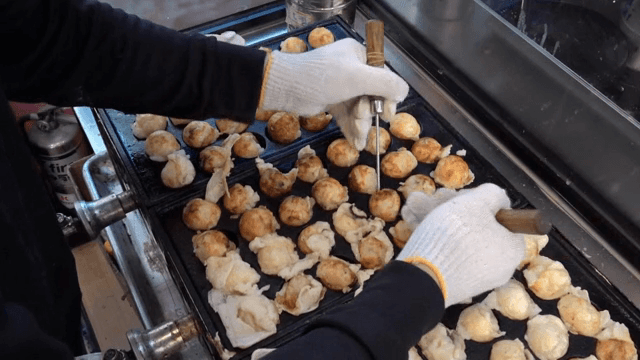 Takoyaki being cooked on a hot griddle