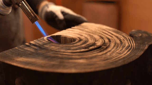 나무 조각품 표면을 그을리는 토치