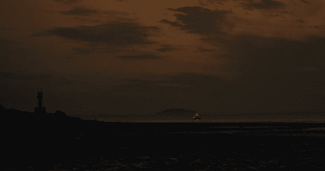 A lighthouse and boat at dusk