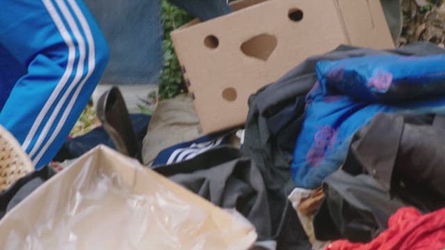 의류수거함에서 쓸만한 물건들을 살펴보는 두 사람