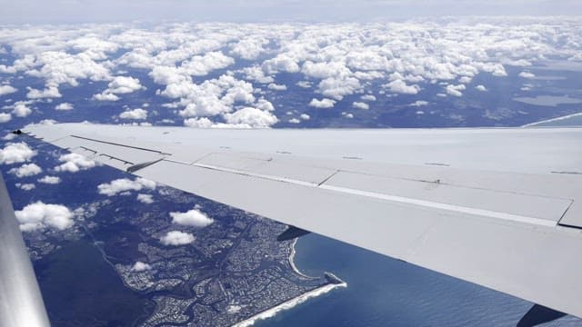 Aerial View of Ocean and Land from Airplane Over City