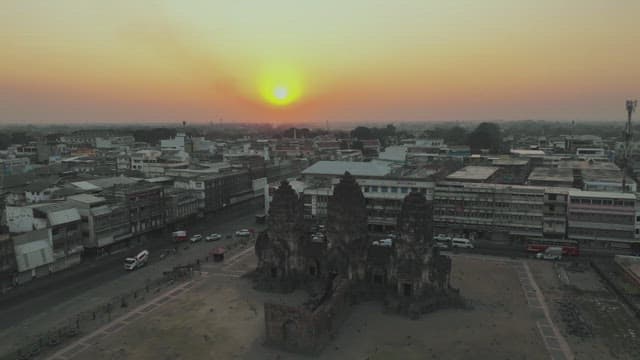 Overview of a Bustling Street with Ancient Temple Ruins and Sunset