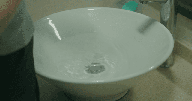 Hands being washed in a white basin